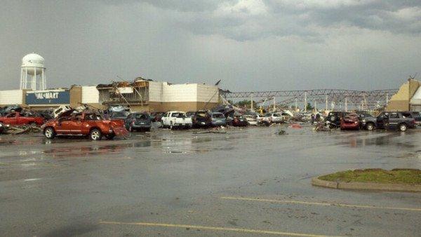 Parking lot outside damaged Walmart store, cars have been pushed into one another, or tossed on top of others.